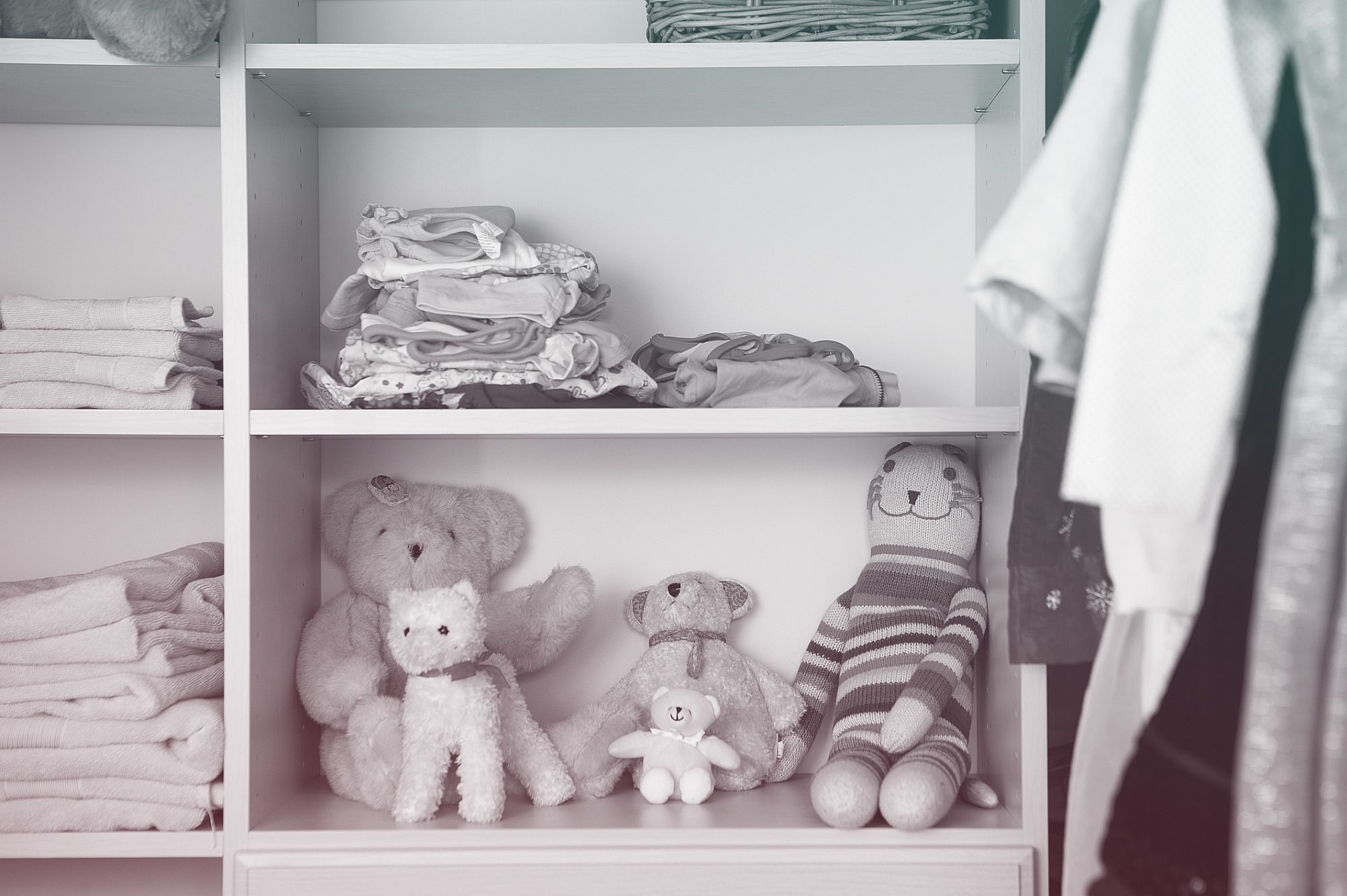 Stuffed animals, clothing and towels on shelves in closet